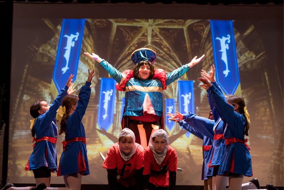 A group of people are performing on a stage in front of a large screen.