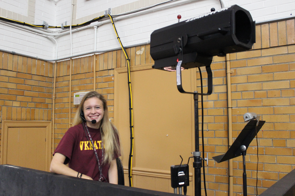 A woman wearing a maroon shirt that says vkat