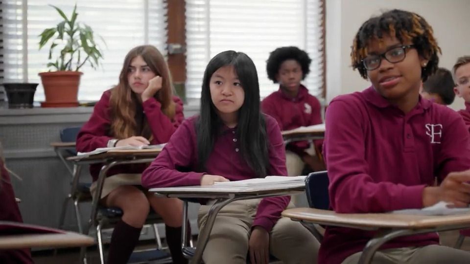A group of students are sitting at their desks in a classroom.