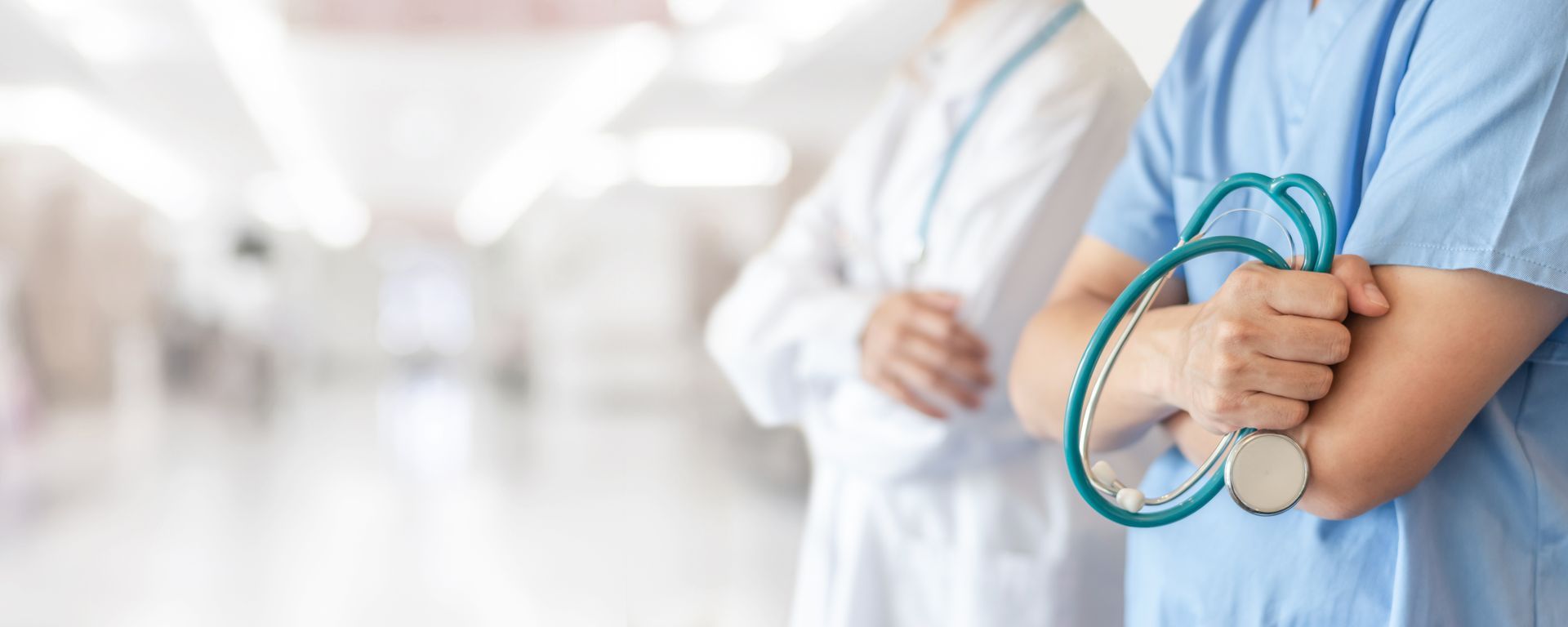 Healthcare professionals standing in hospital hallway holding stethoscope Healthcare professionals standing in hospital hallway holding stethoscope