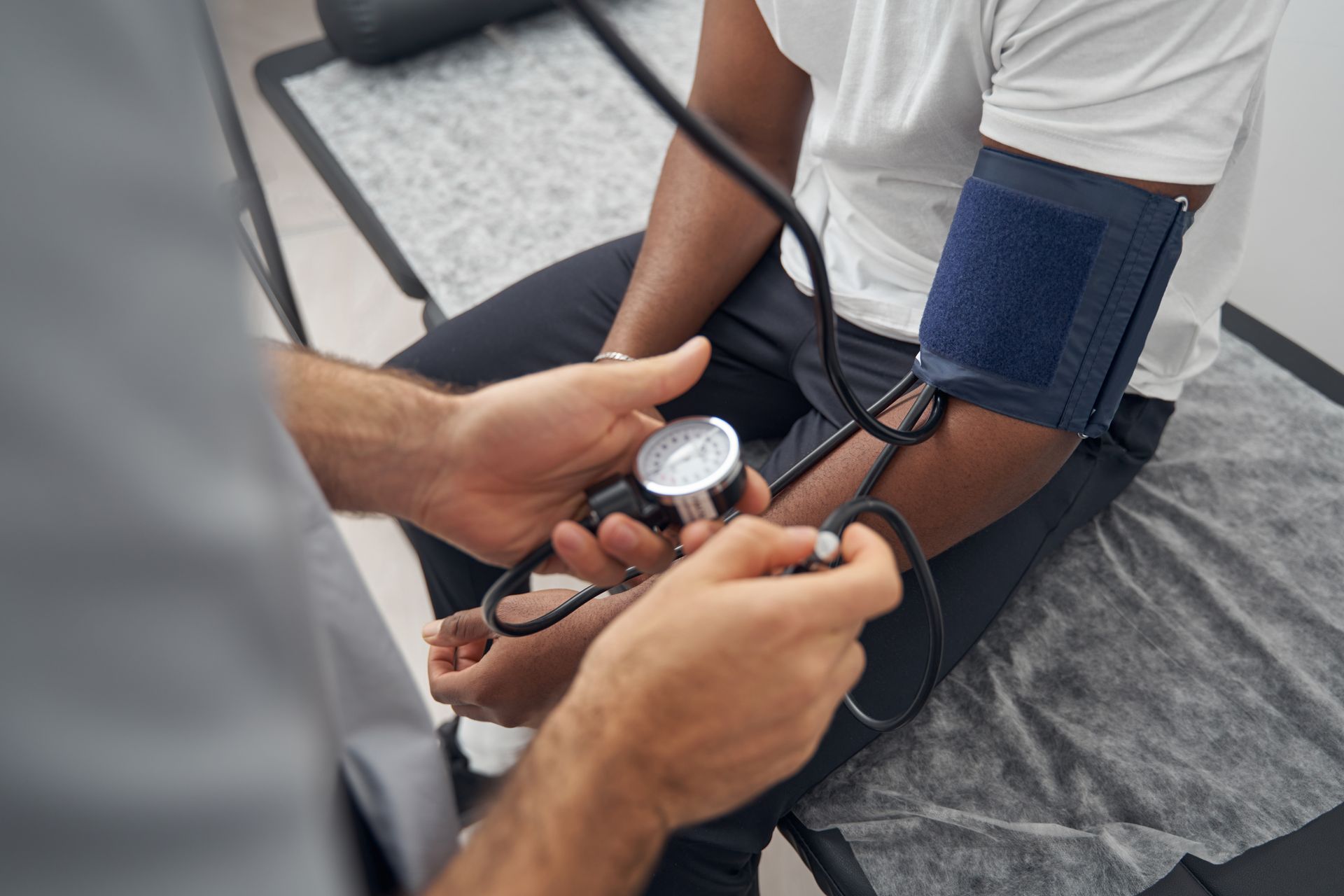 A clinician measures a patient’s blood pressure during a routine checkup in a clinic.