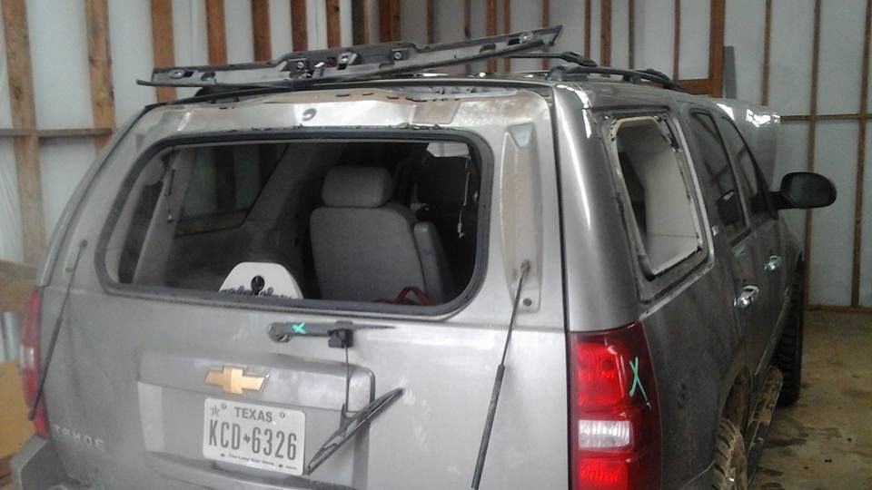 A silver suv with a ladder on top of it is parked in a garage.