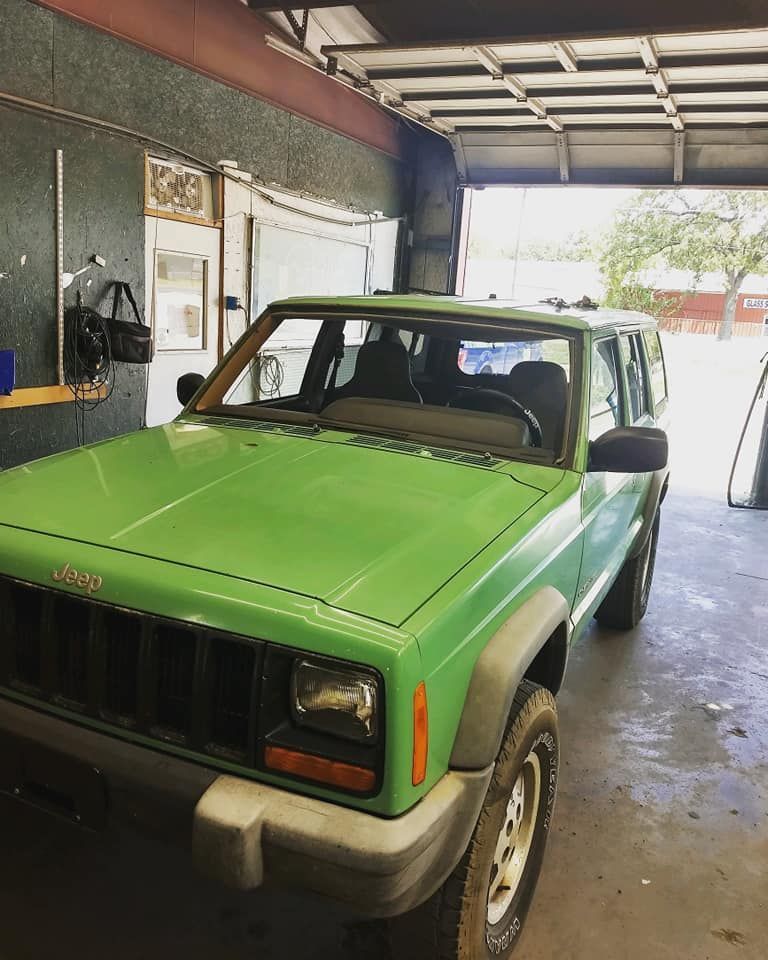 A green jeep is parked in a garage.