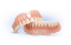 A pair of dentures sitting on top of each other on a white surface.