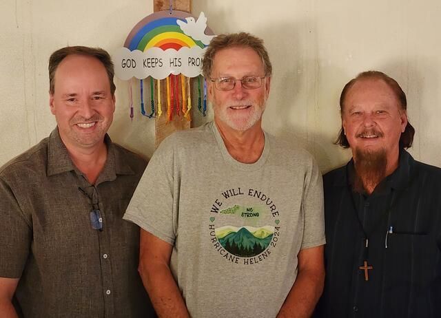 Three men are standing in front of a sign that says god keeps his promises