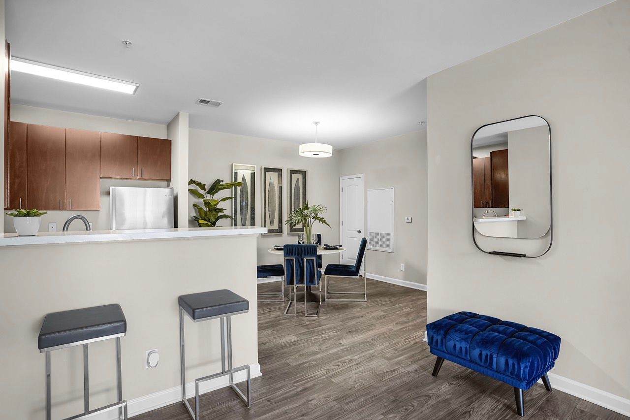 Open-concept kitchen and dining area in a modern apartment with a bar counter, stools, and a blue tufted bench.