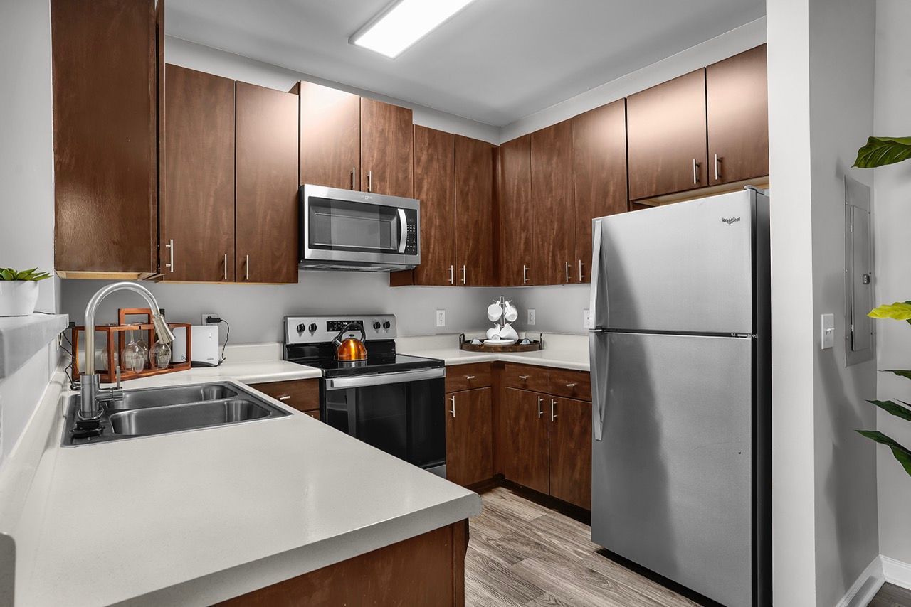 Modern apartment kitchen with dark wood cabinets and stainless steel appliances.