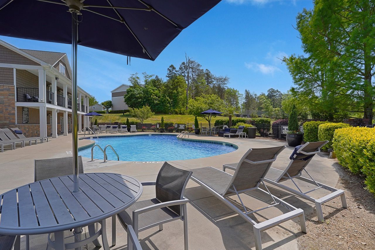 Outdoor pool at a multifamily community with lounge chairs and umbrellas.