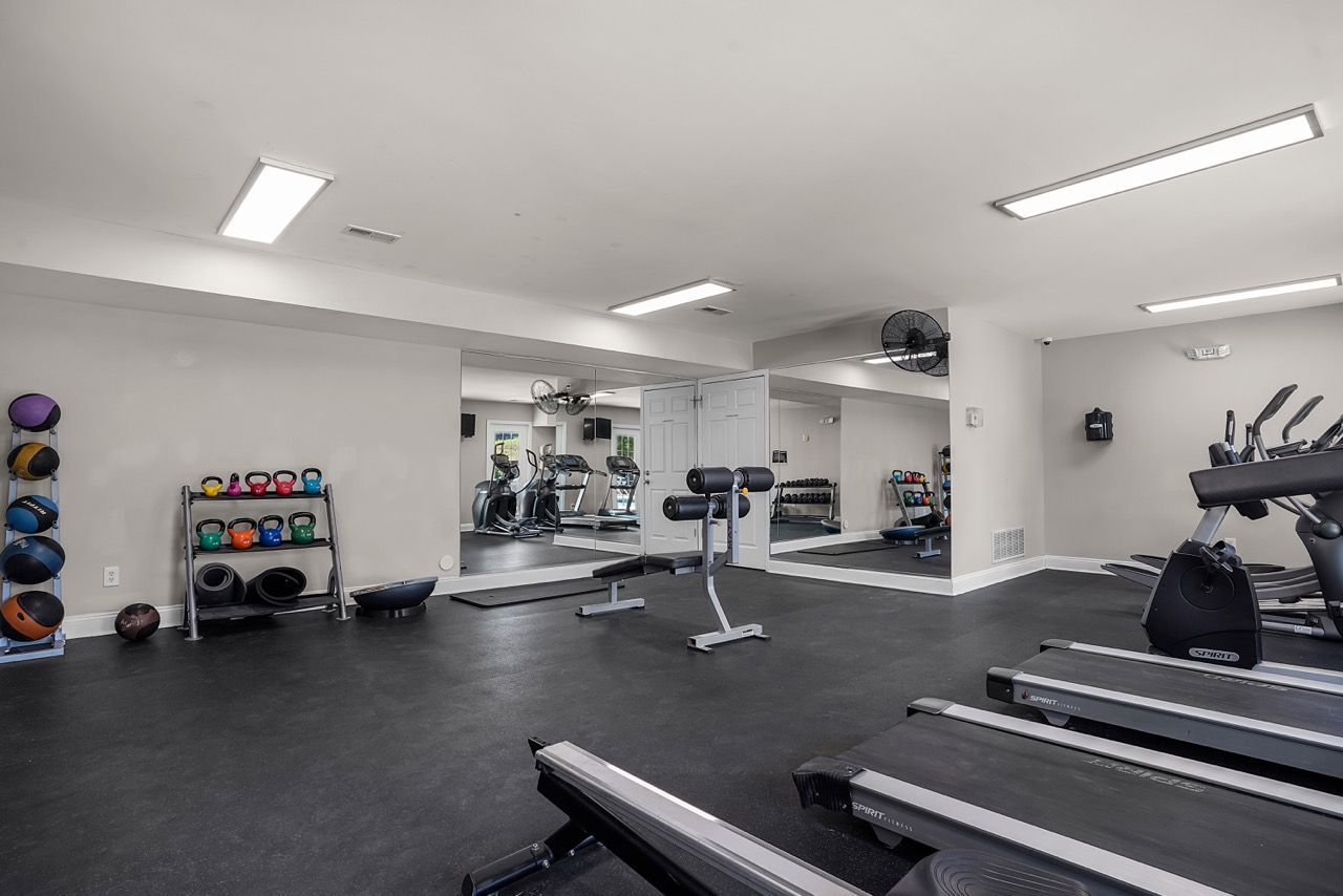 Interior of a resident gym with treadmills, weights, and mirrors.