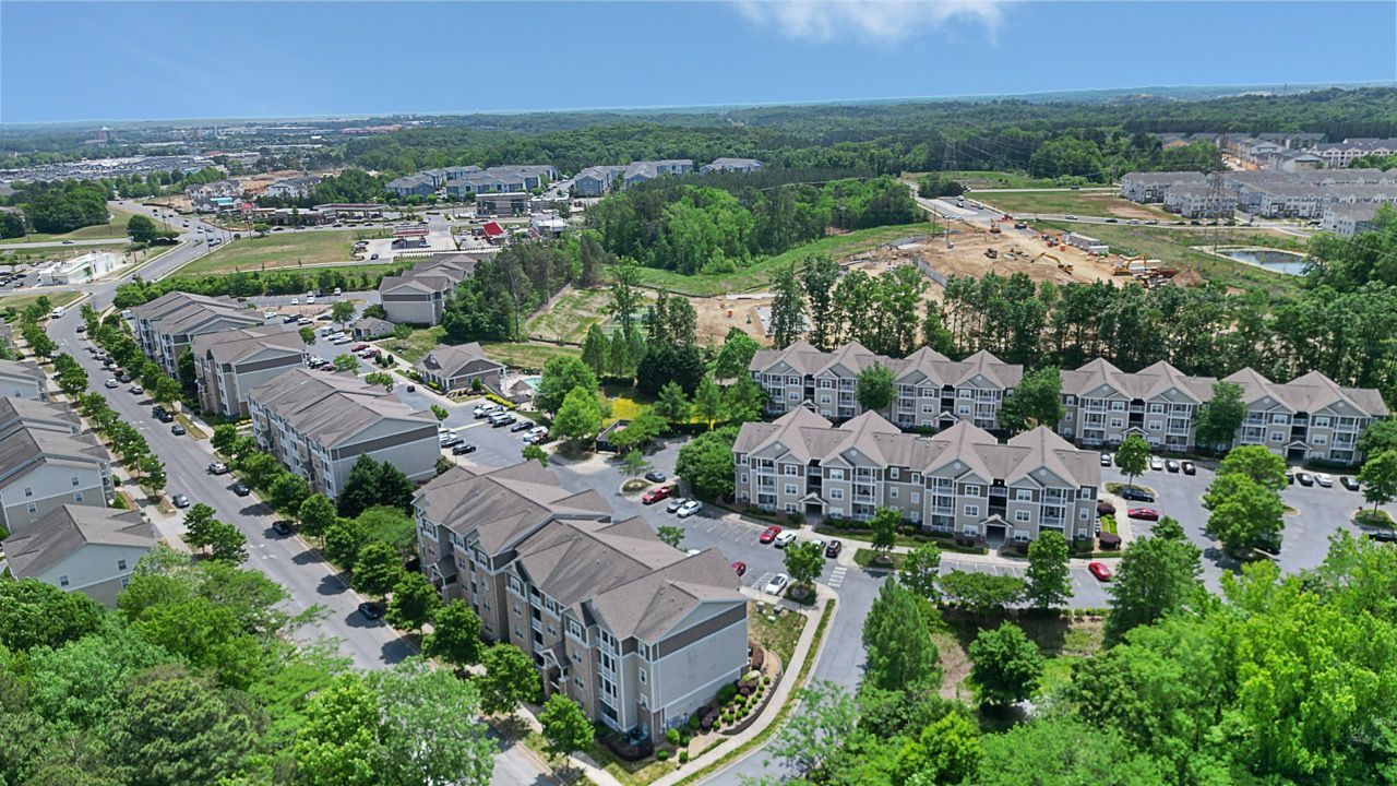 Aerial view of a large apartment community with multiple buildings, parking lots, and trees.