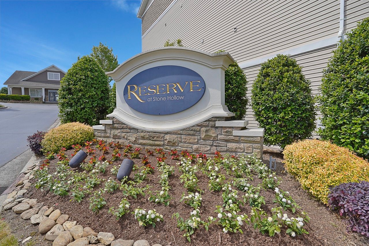 Exterior sign for Reserve at Stone Hollow with landscaped flower bed
