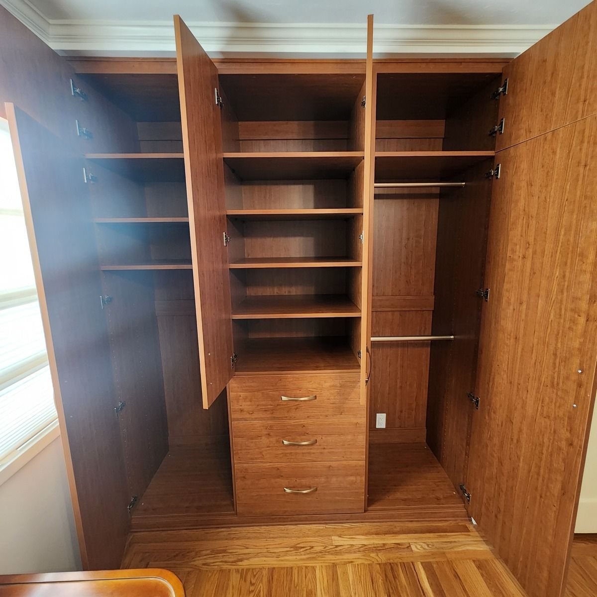 A closet with the doors open and lots of shelves and drawers