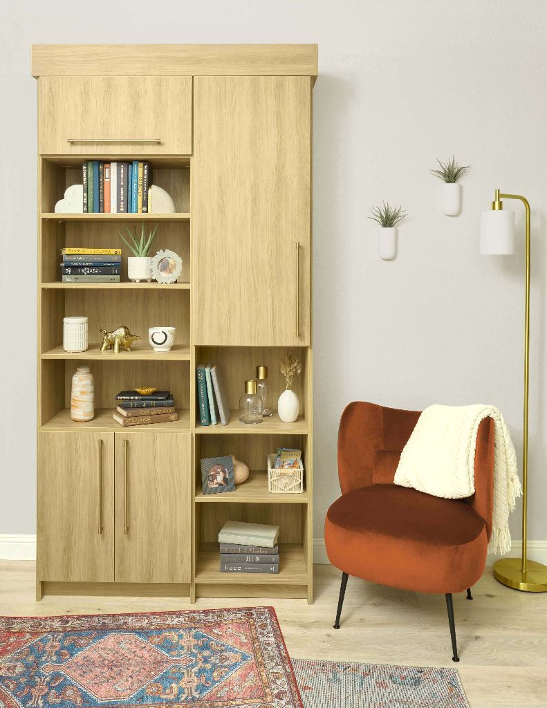 A wooden bookcase with open shelving and closed cabinets, next to a red armchair and floor lamp.