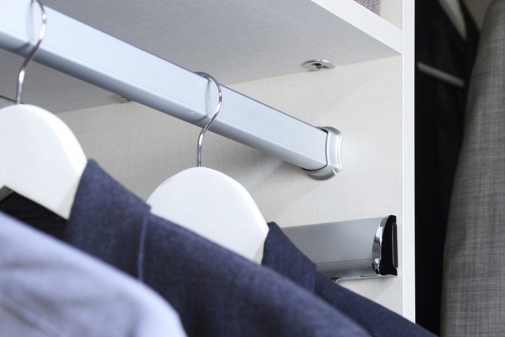 a closet with shirts and jackets hanging on hangers