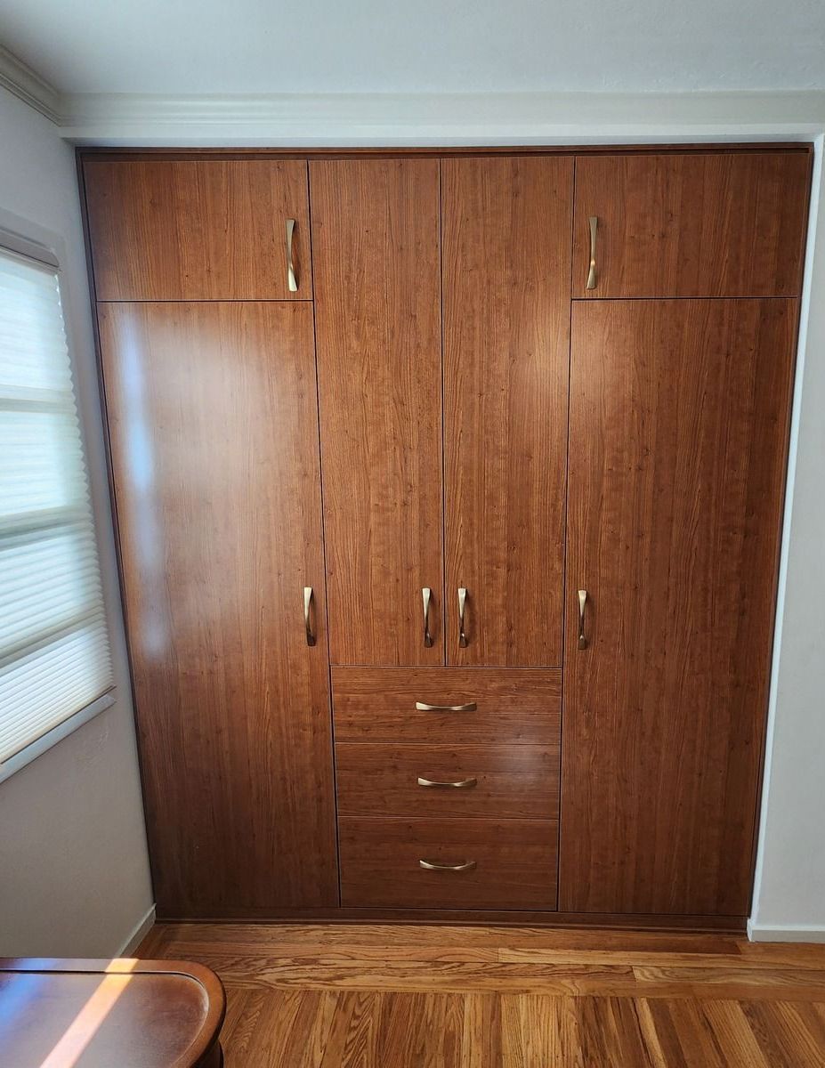 A large wooden wardrobe with drawers and cabinets in a bedroom.