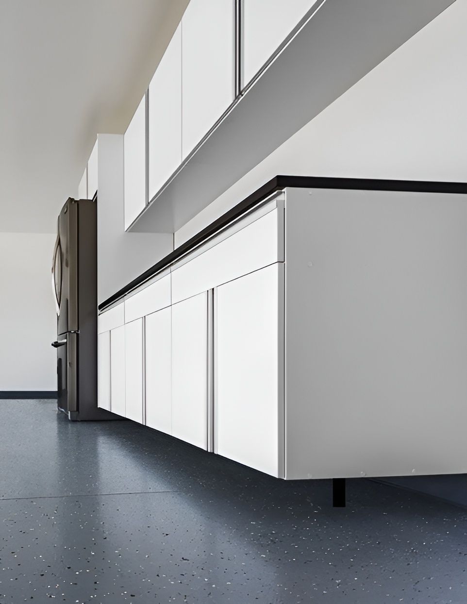 a garage with white cabinets and a black refrigerator .