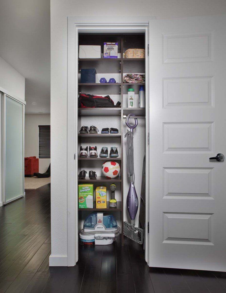 a utility closet with a vacuum cleaner and a soccer ball on the shelves .