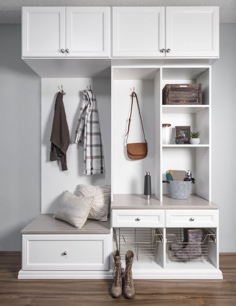 a mudroom with white cabinets , shelves , and a bench .