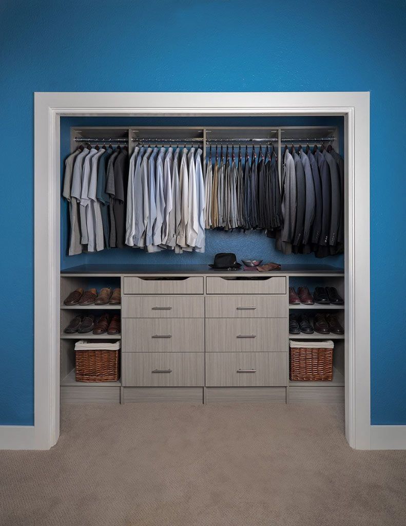 a reach in closet filled with clothes and a dresser .