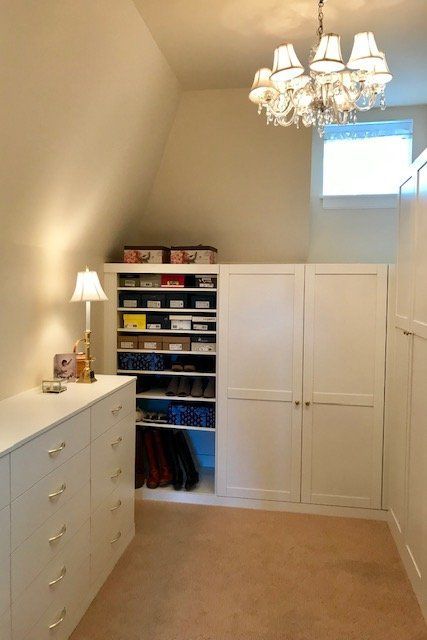 A walk in closet with lots of shelves and a chandelier