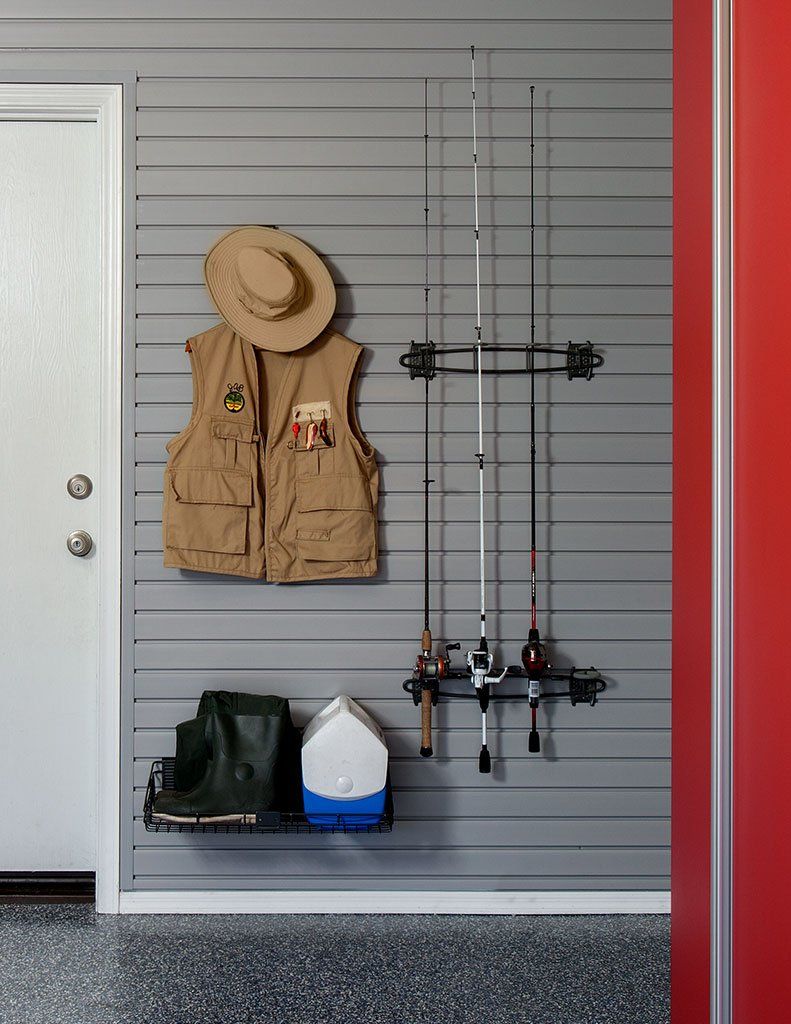 a fishing vest and hat are hanging on a slatwall system in a garage .