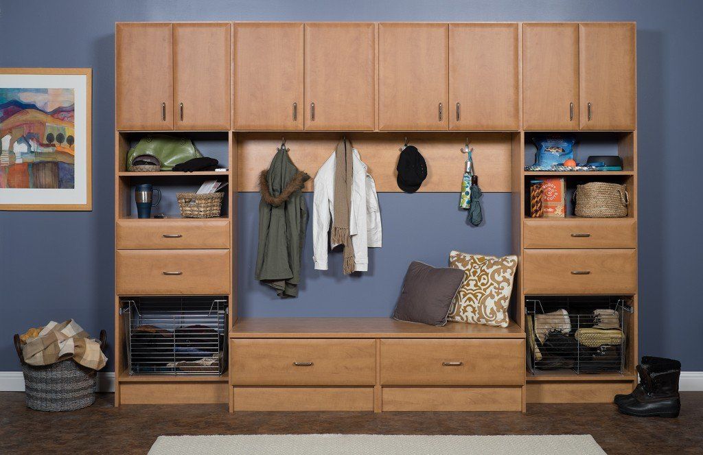 Wooden wall unit with cabinets, shelves, hanging clothes, drawers, and a cushioned bench in a living room