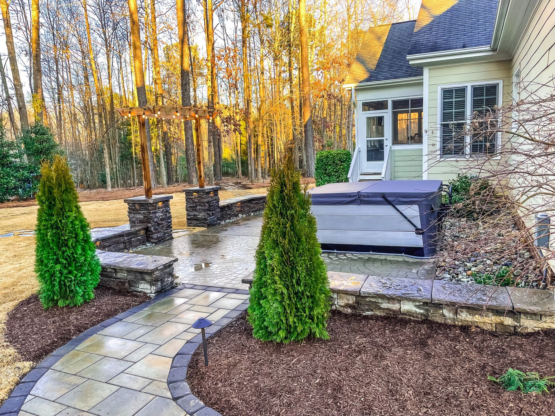 A walkway leading to a house with a hot tub in the backyard.