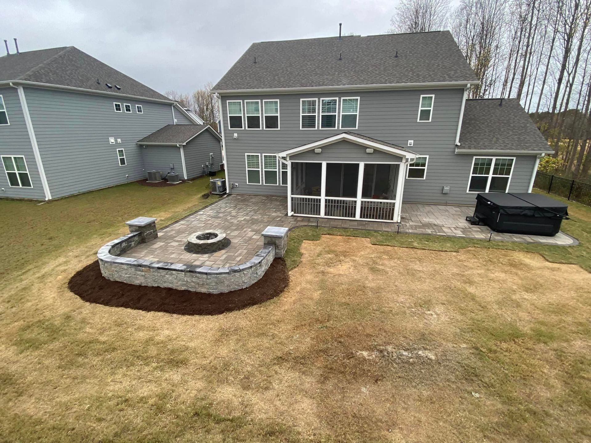 A large house with a screened in porch and a fire pit in the backyard.