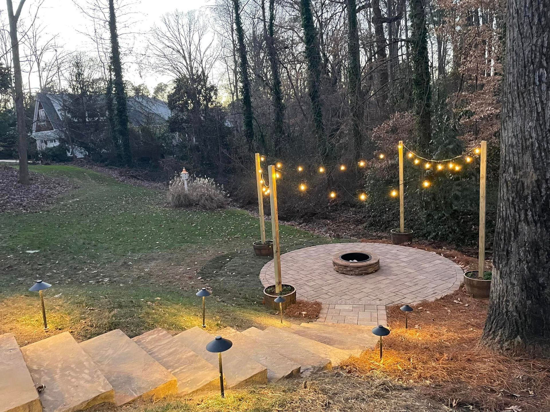 A fire pit in the middle of a yard with stairs leading to it.