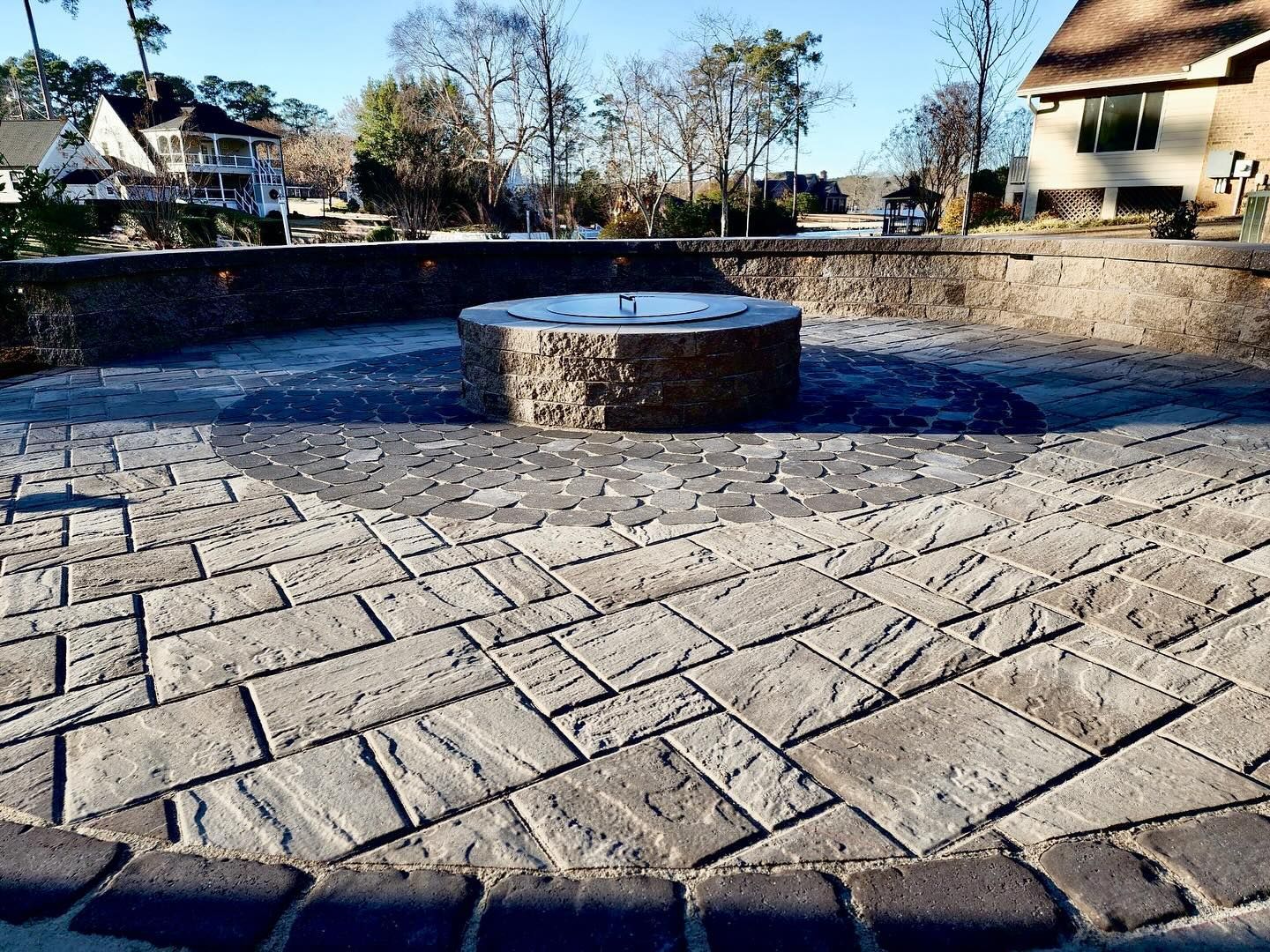 A stone patio with a fire pit in the middle of it