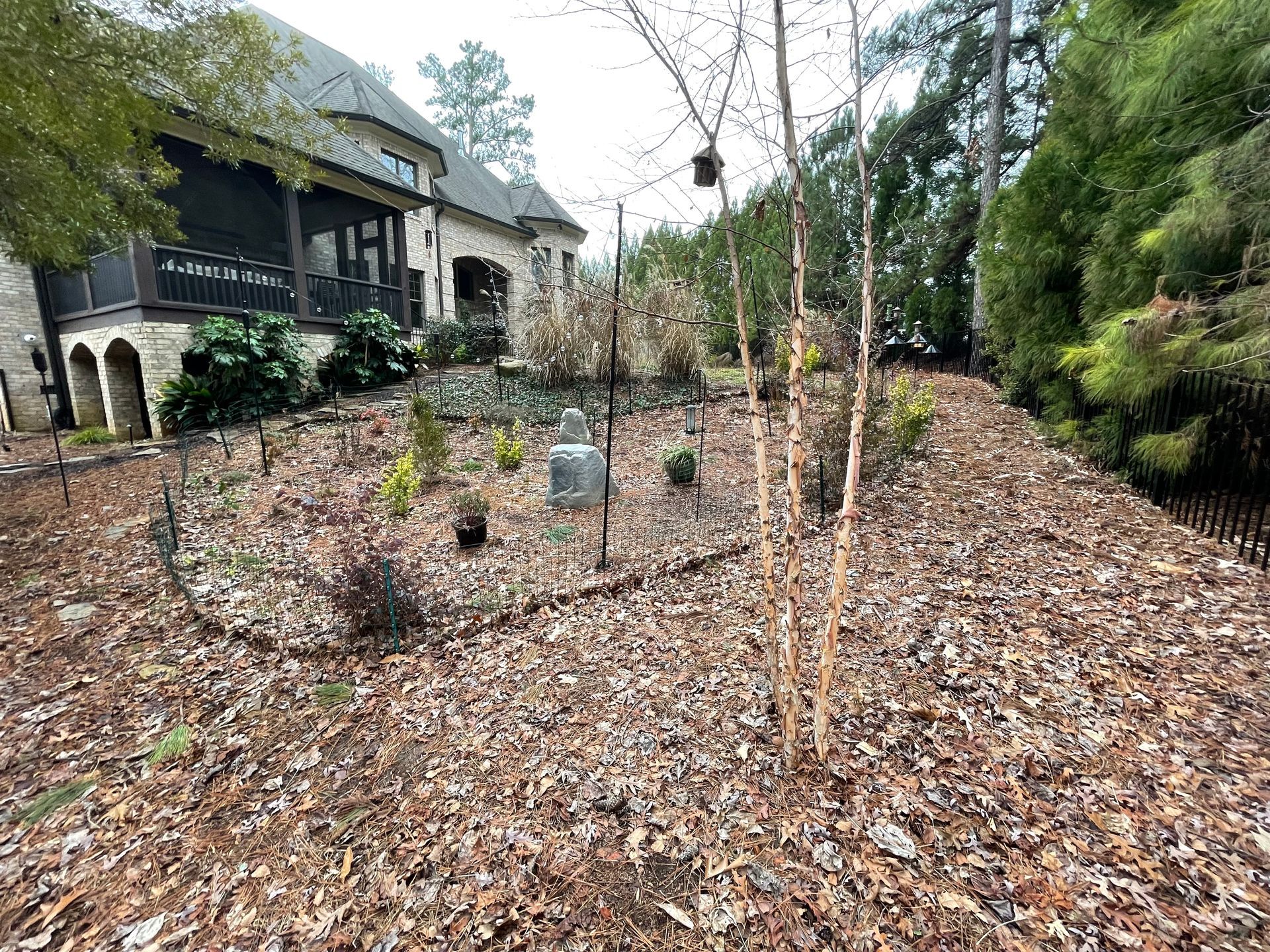 A large house is sitting on top of a hill surrounded by trees and mulch.