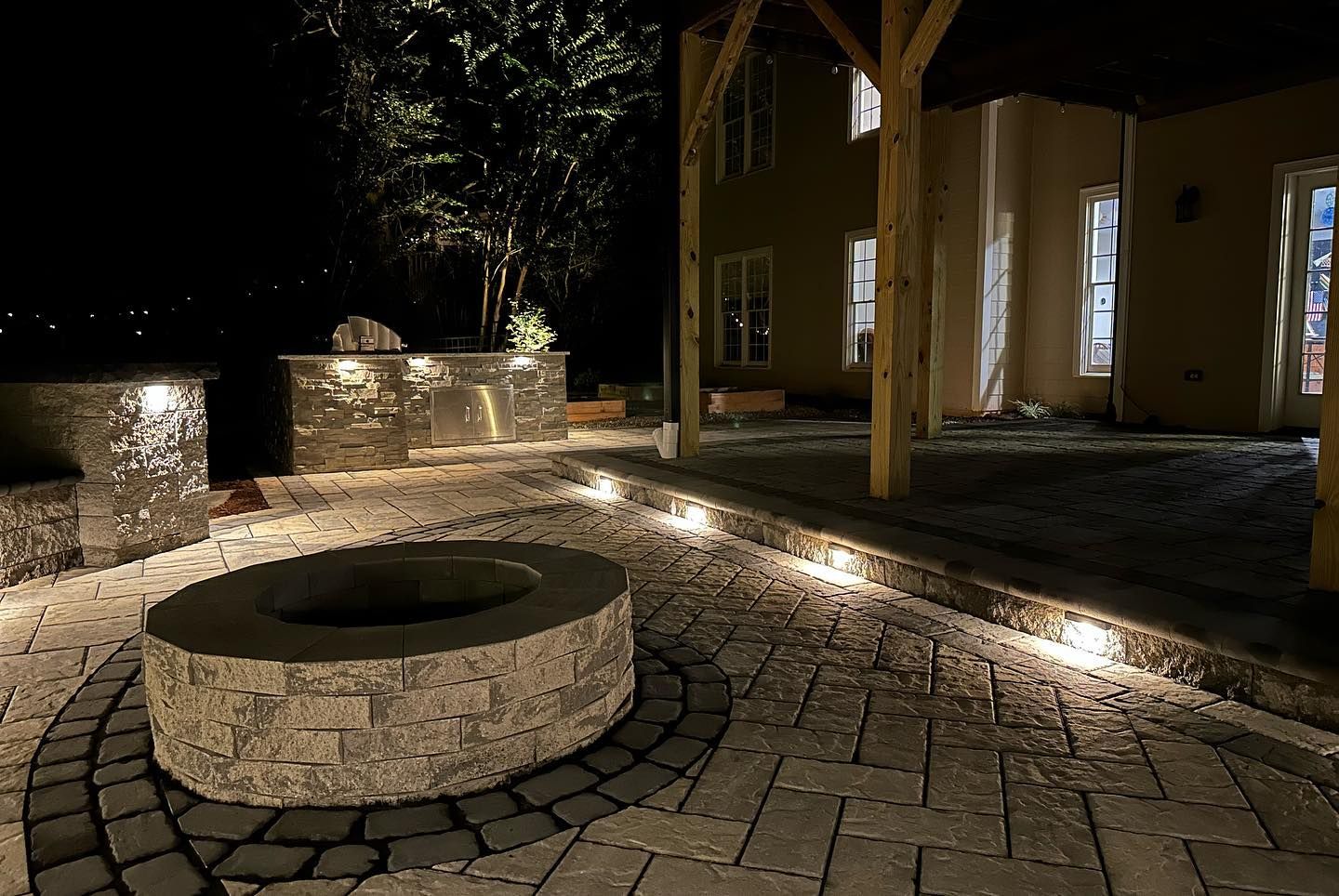A fire pit is lit up at night in front of a house.