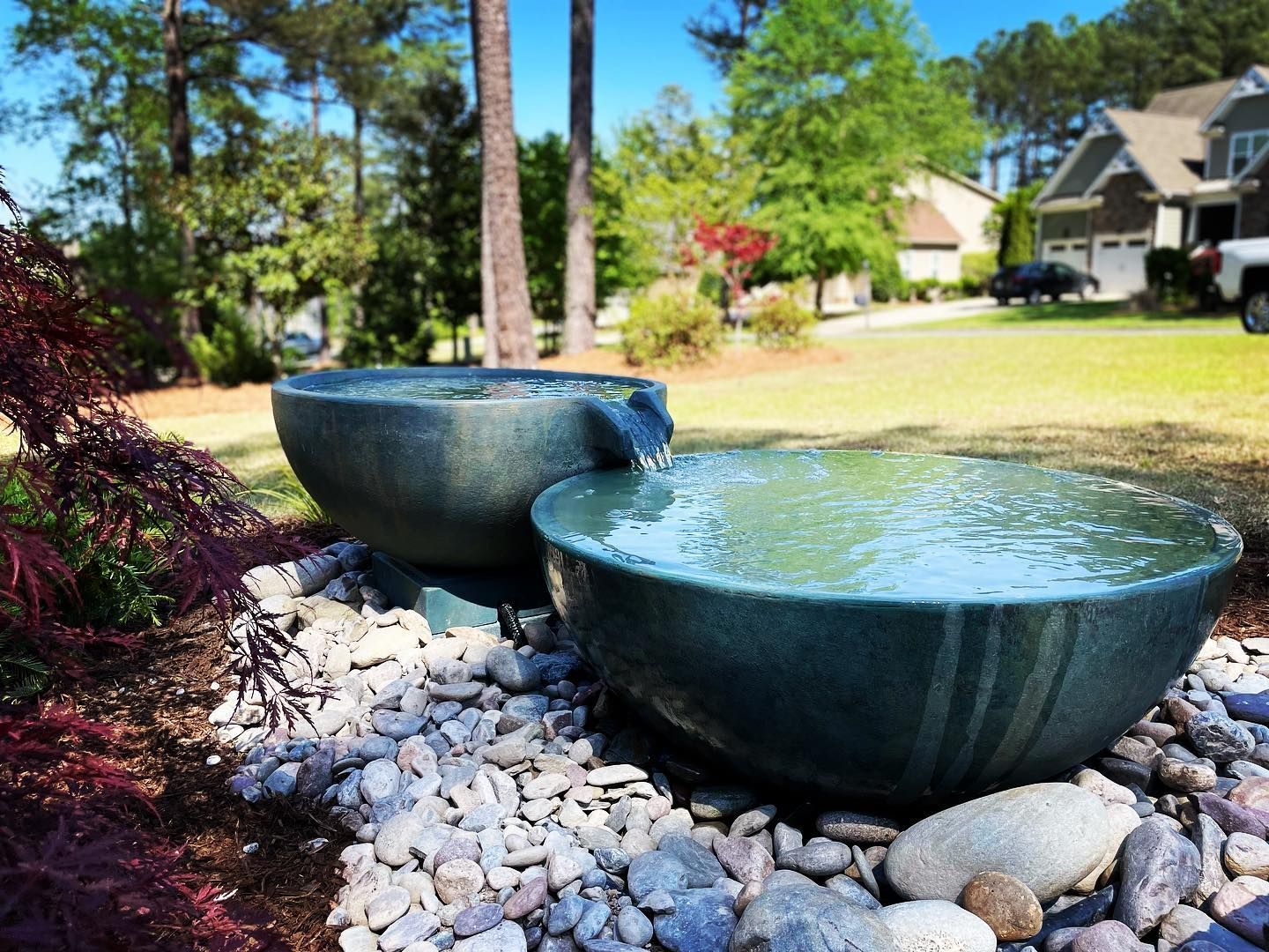 Two bowls filled with water are sitting next to each other in a garden.