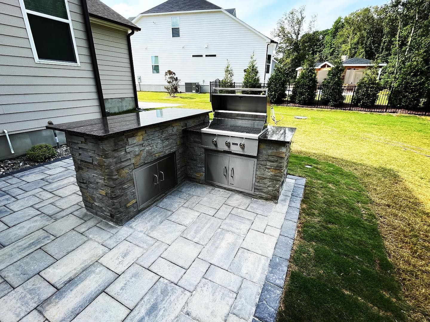 A grill is sitting on a patio next to a house.