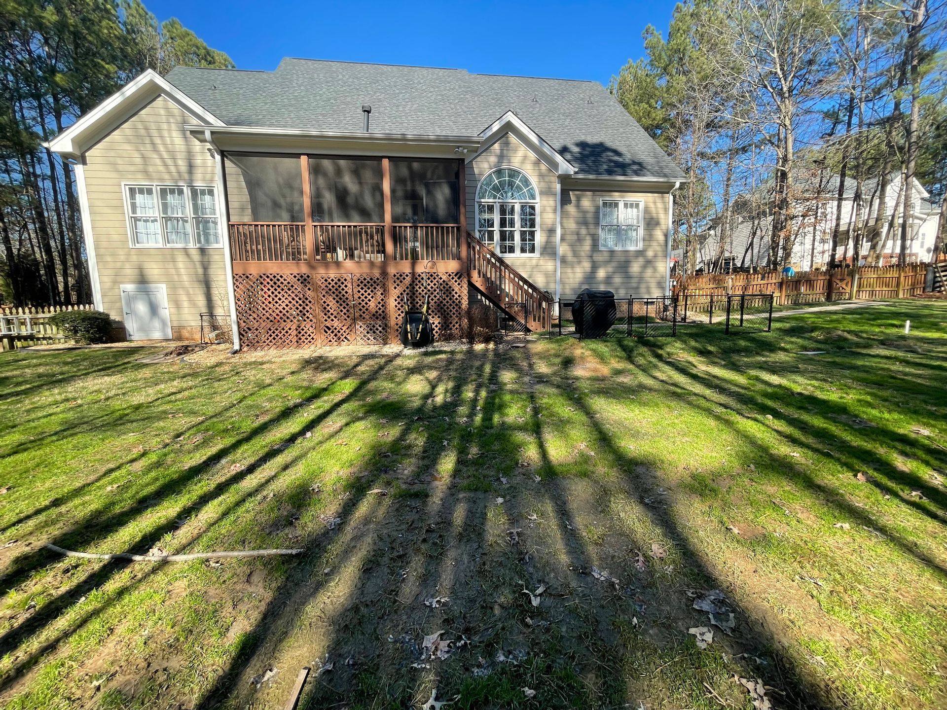 A house with a screened in porch and a large lawn in front of it.