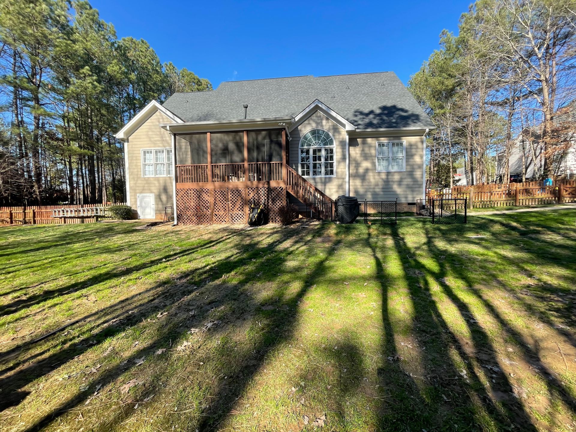 A house with a screened in porch and a large lawn in front of it.