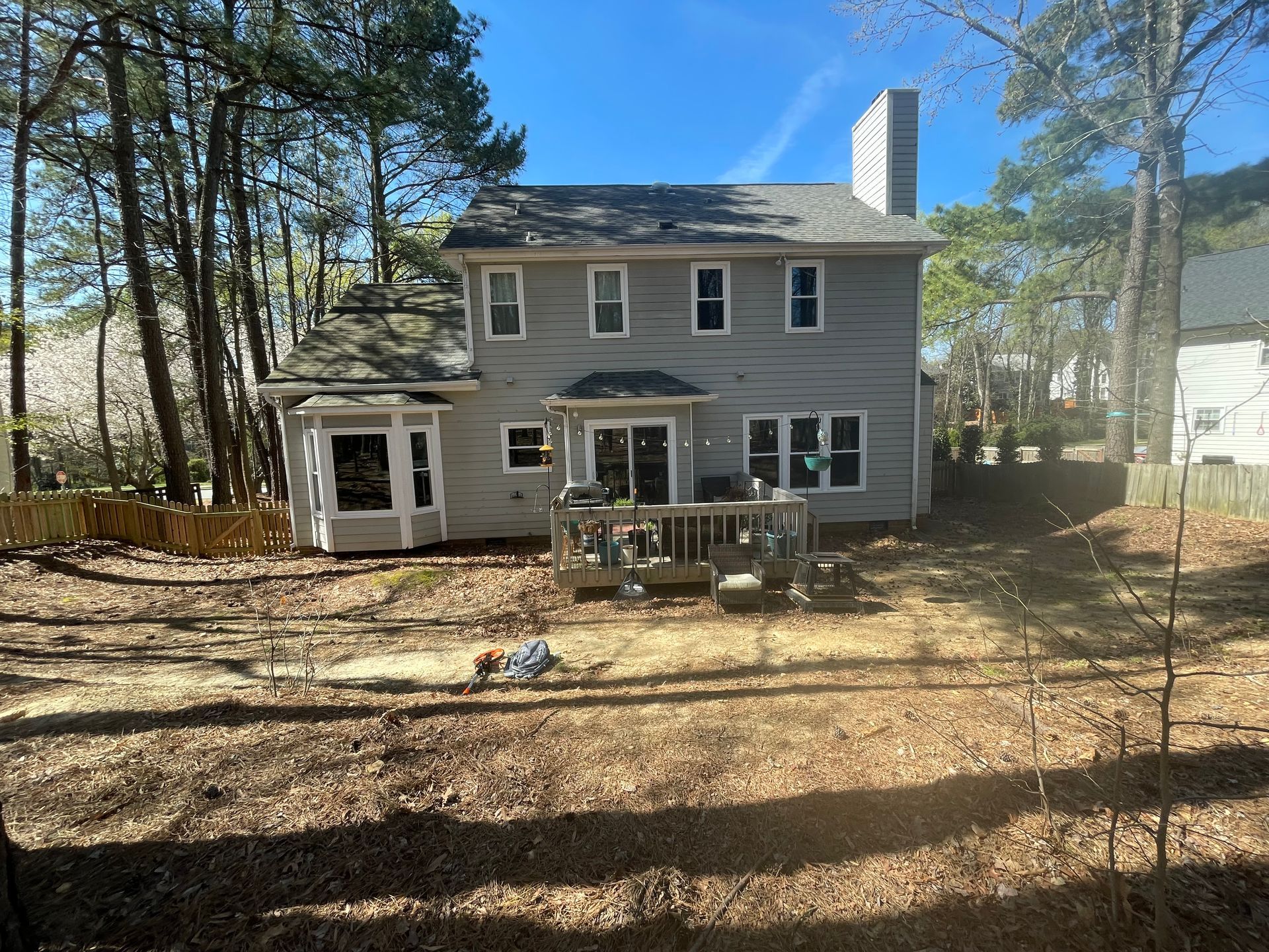 A large house with a large deck in the backyard surrounded by trees.