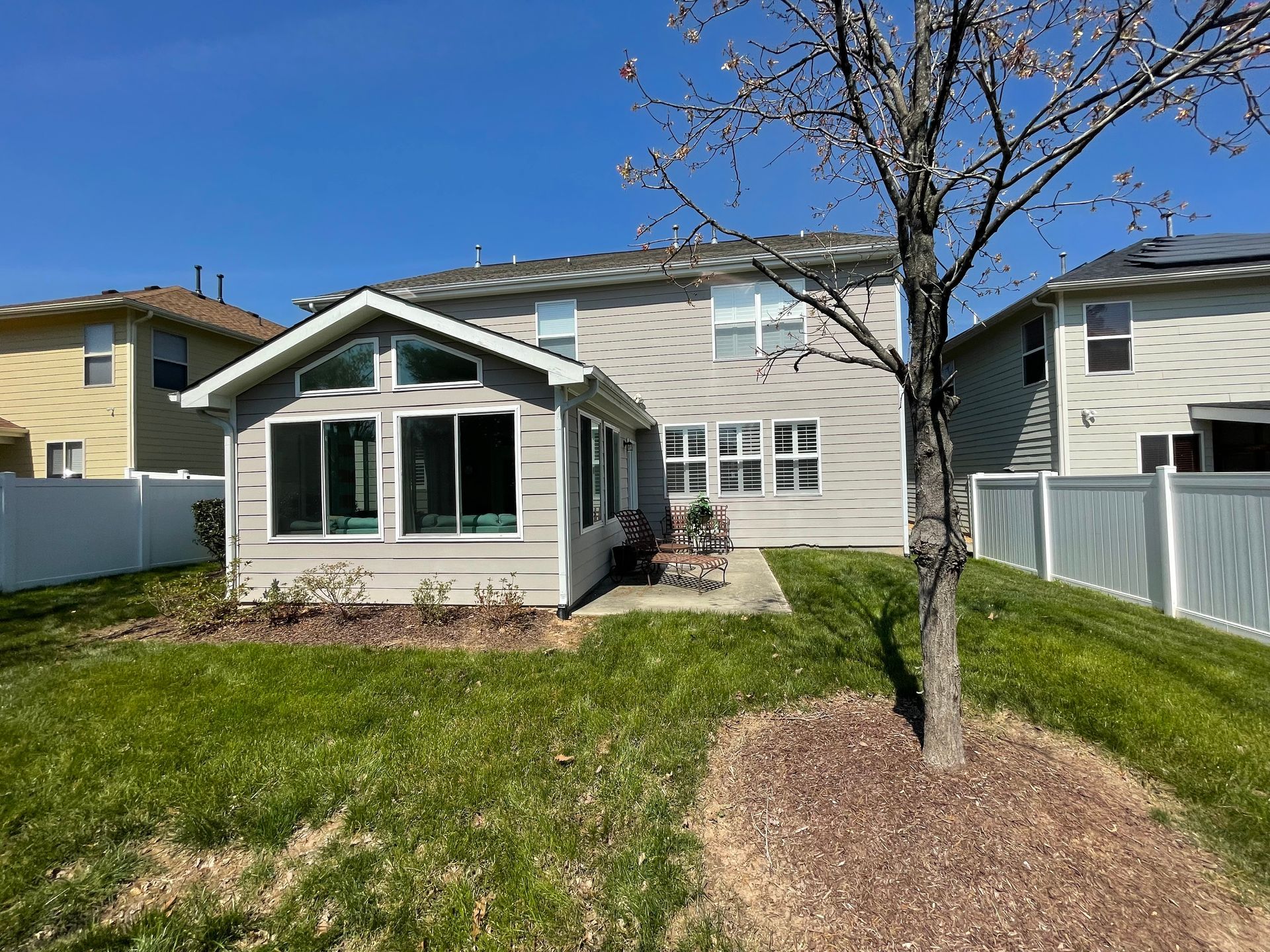 The backyard of a house with a tree in the middle of it.