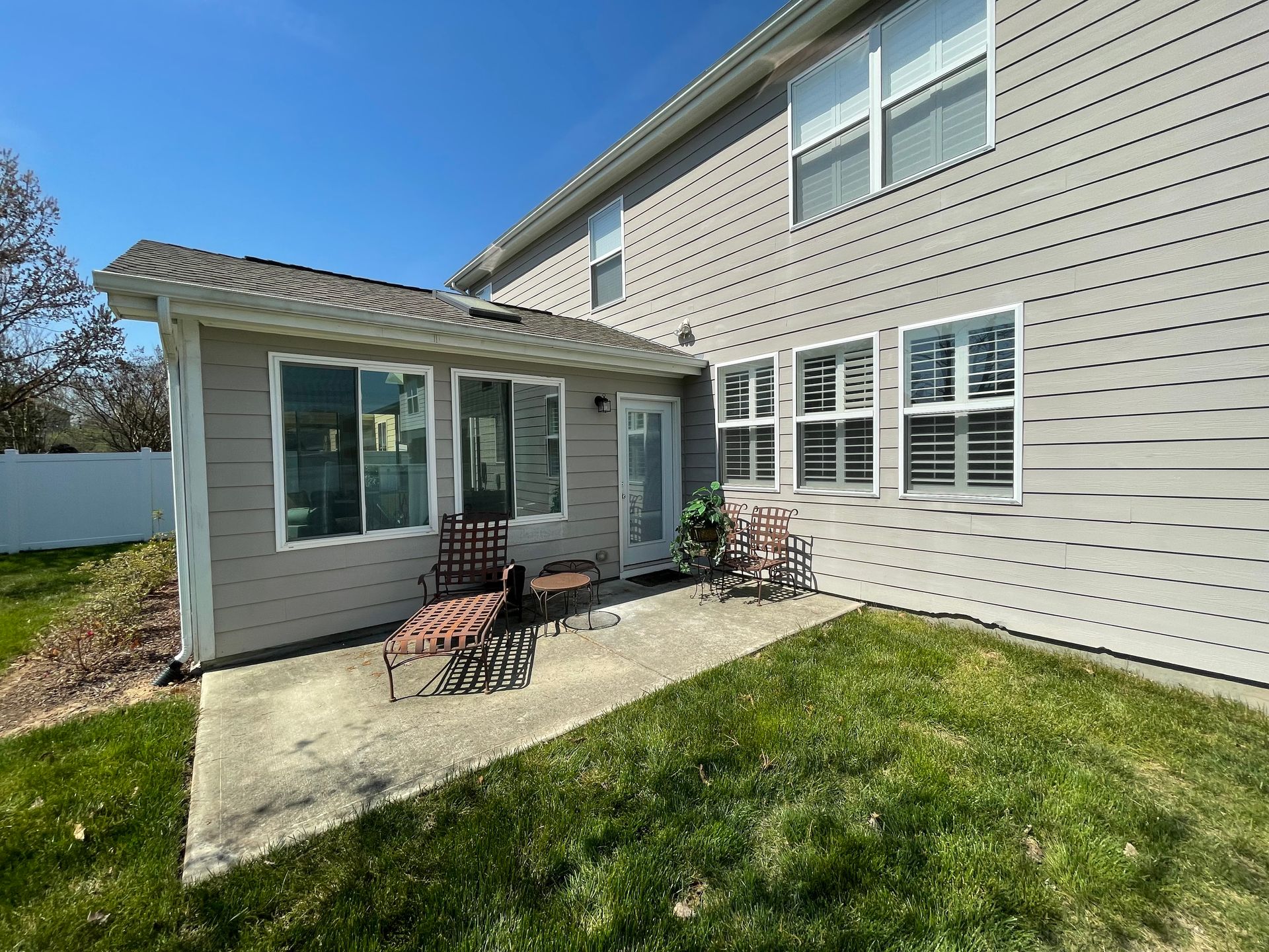 The backyard of a house with a patio and chairs.