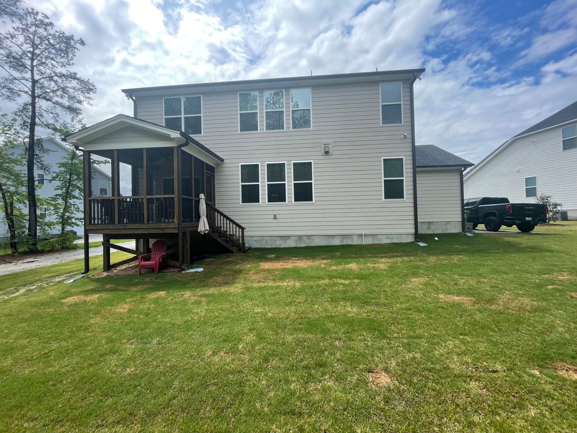 A house with a screened in porch and a truck parked in front of it.