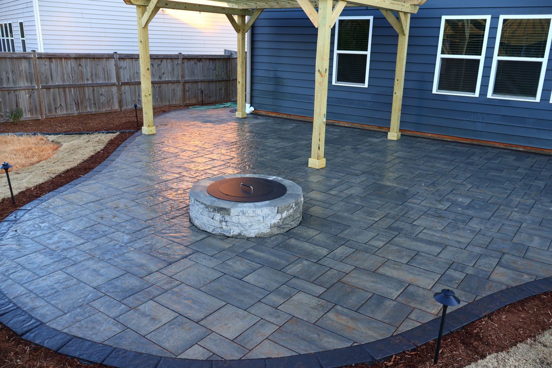 A fire pit is sitting on a patio next to a house.