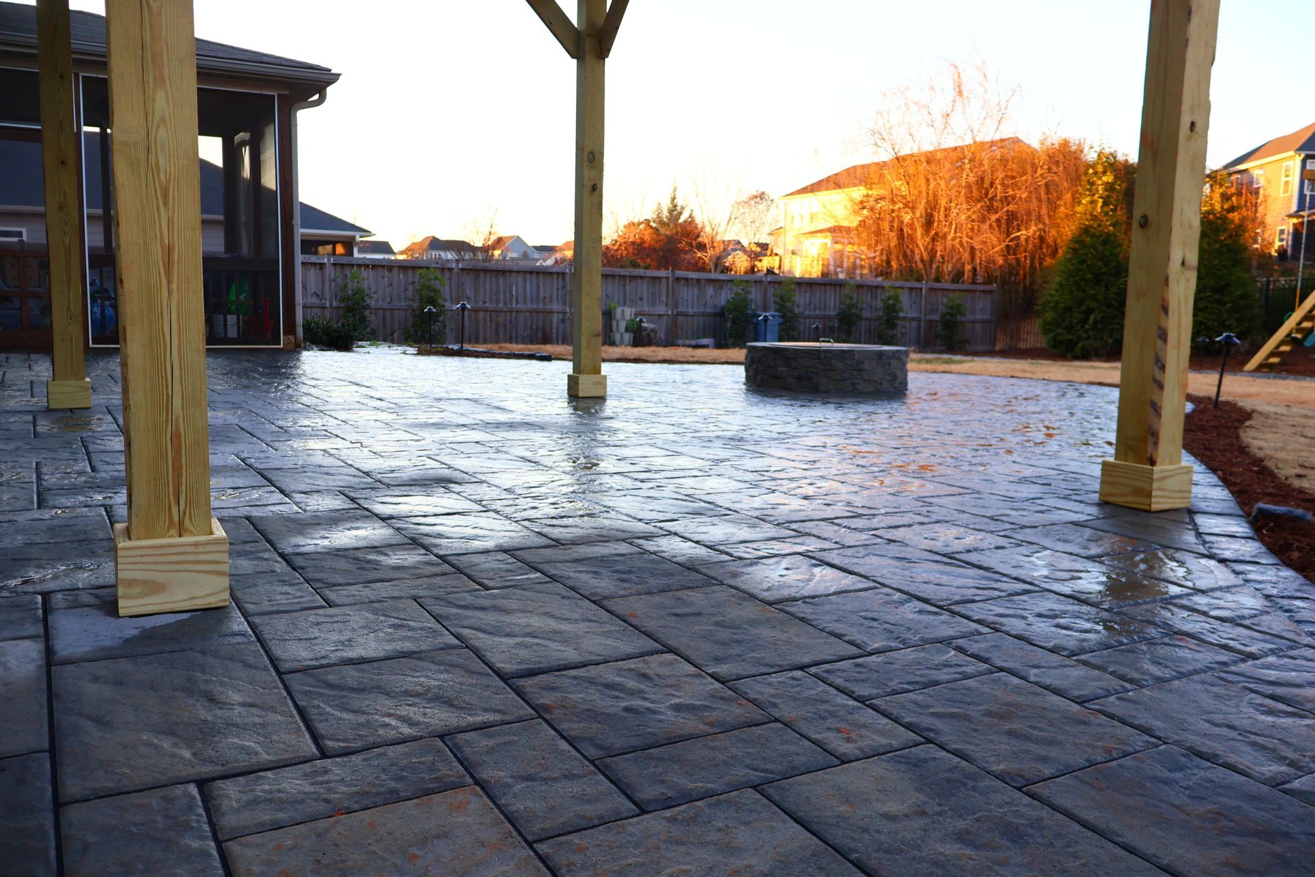 A patio with a pergola and a playground in the background