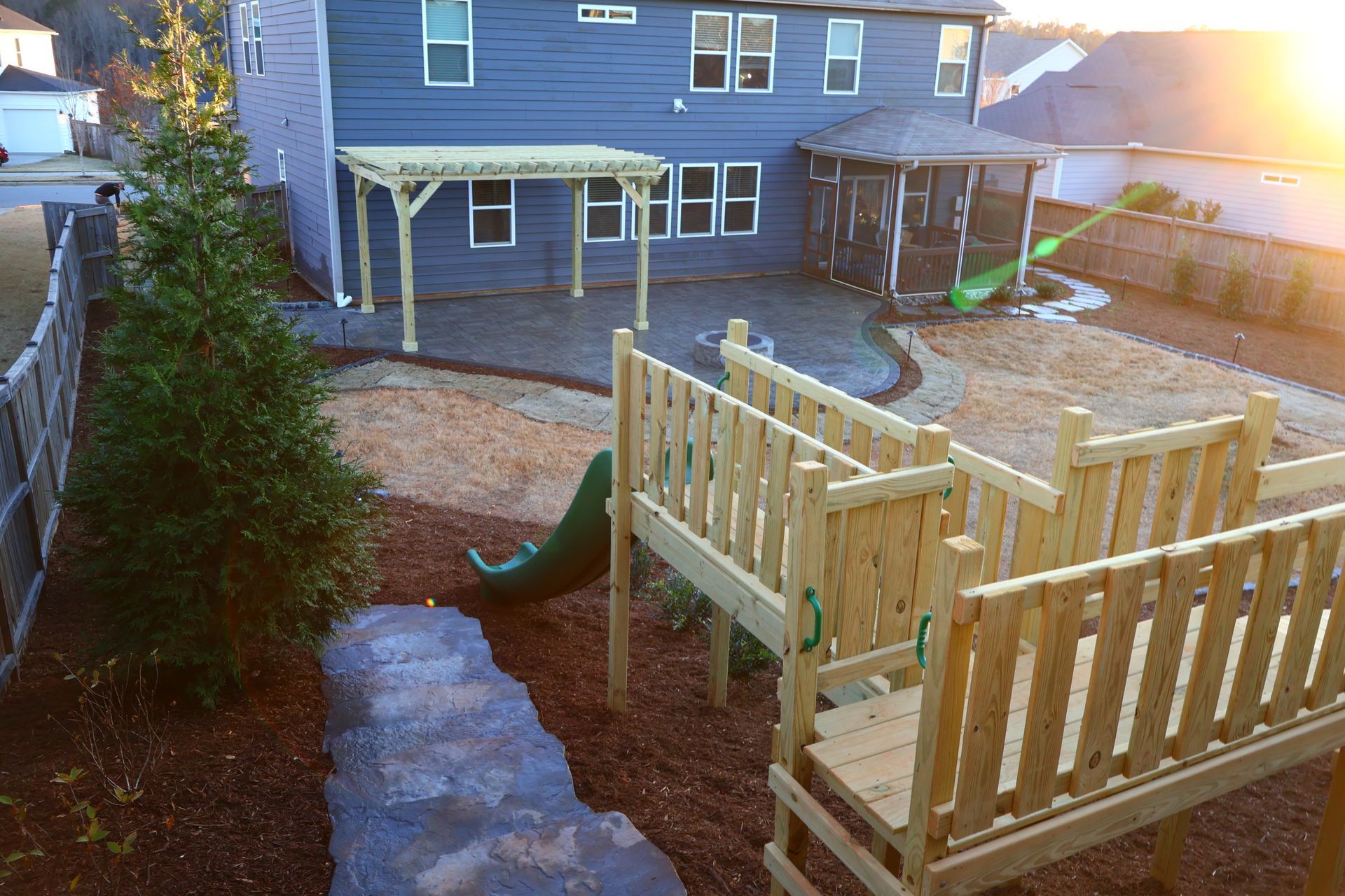 A wooden playground with stairs and a slide in front of a house