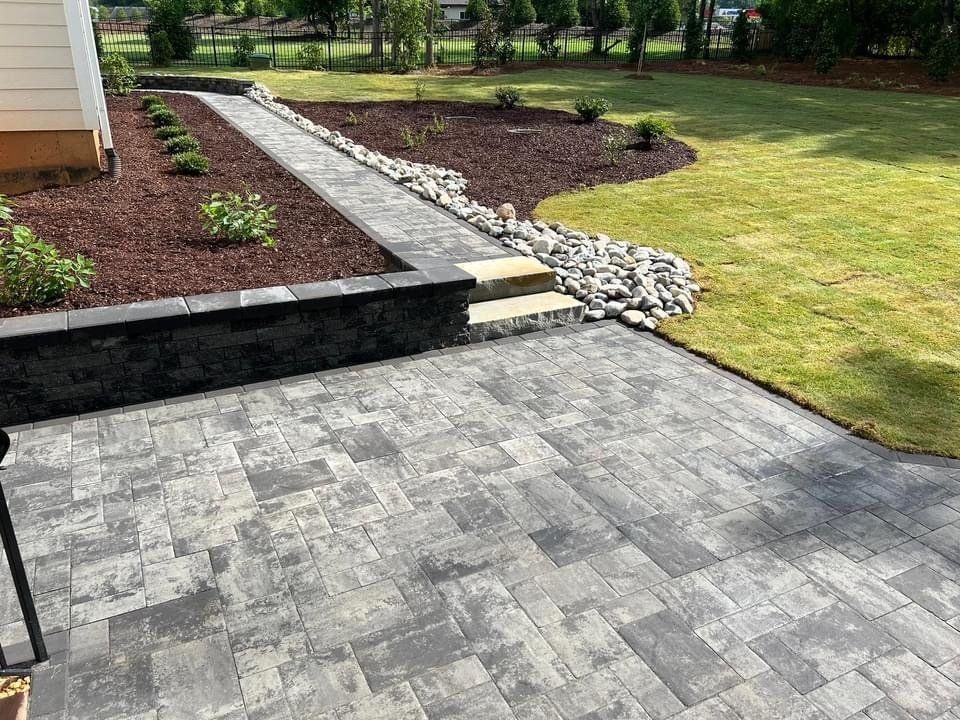 A patio with a walkway leading to a lush green yard.