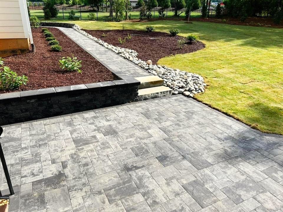 A patio with a walkway leading to a lush green yard.