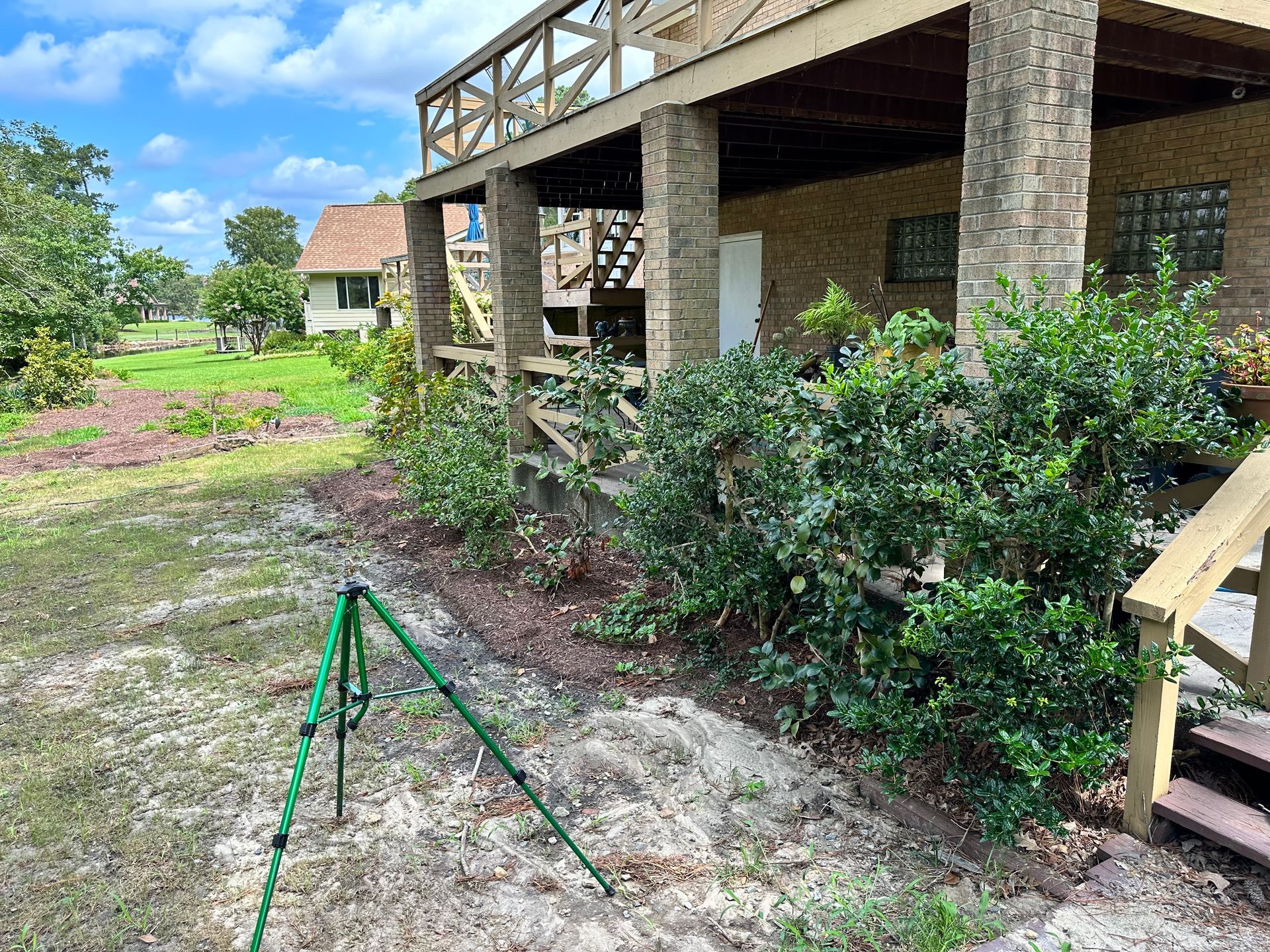 A tripod is sitting in the dirt in front of a house.