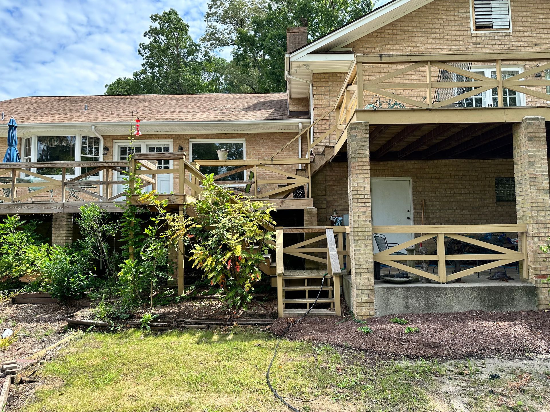 A large brick house with a wooden deck and stairs.