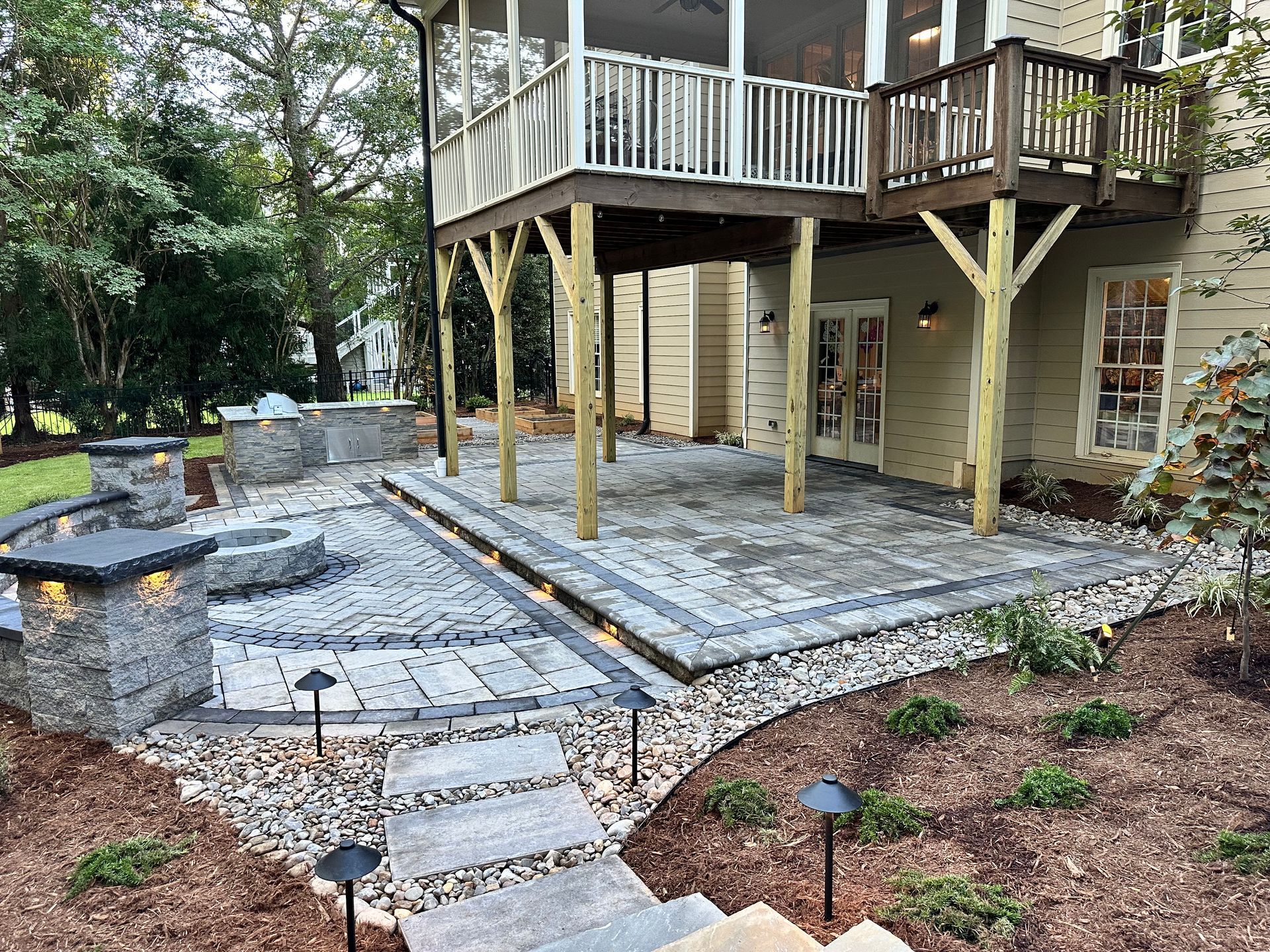 A large patio with a screened in porch and a large deck.