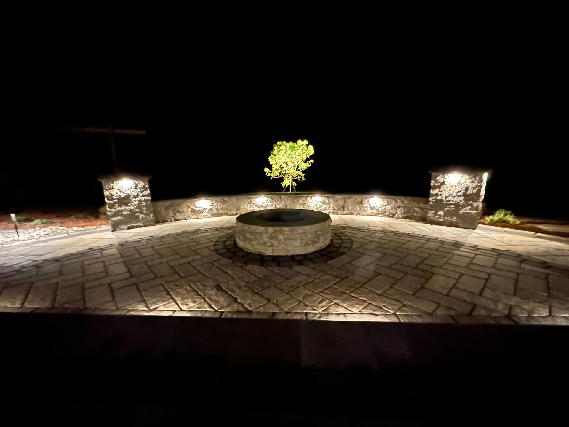 There is a fire pit in the middle of the patio at night.