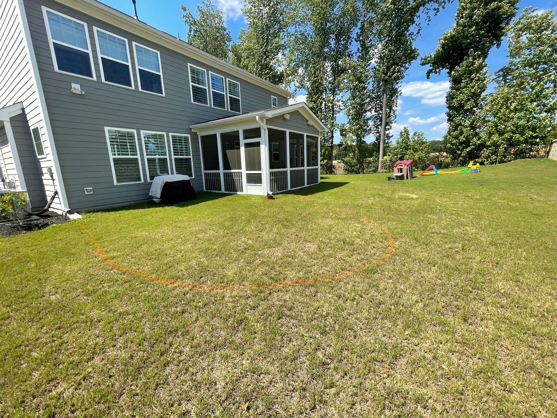 A large house with a screened in porch is sitting on top of a lush green lawn.